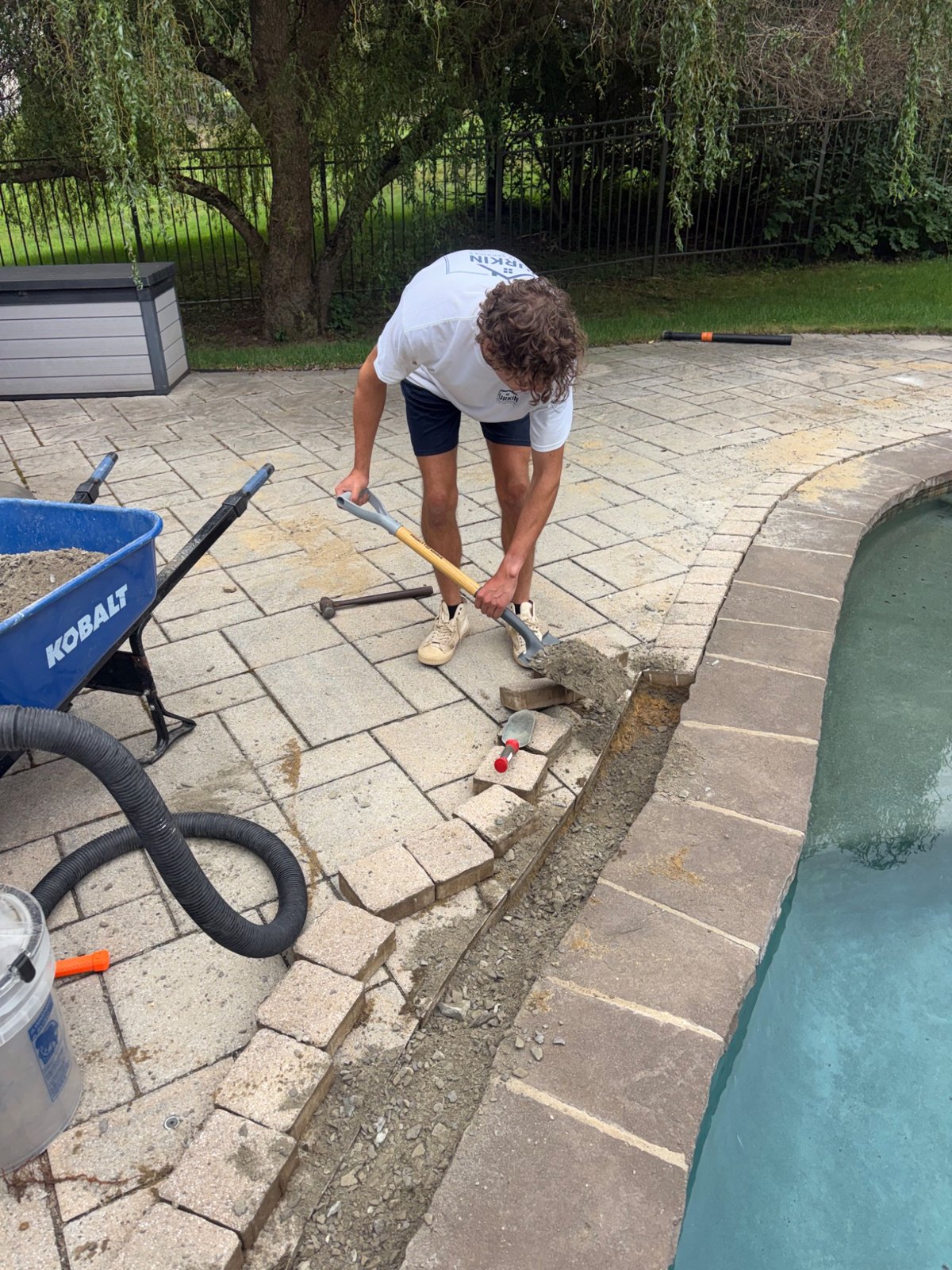 Crew member working on the poolside paver base